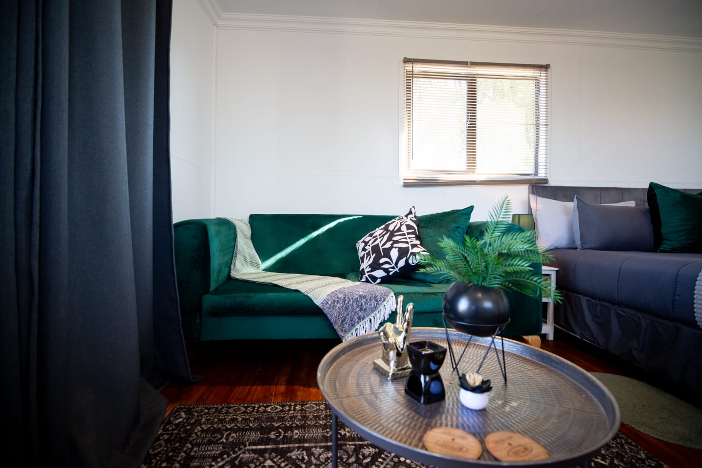 A cozy cabin lounge with an emerald green sofa, soft textures, warm wooden floors, and a quiet place to unwind.